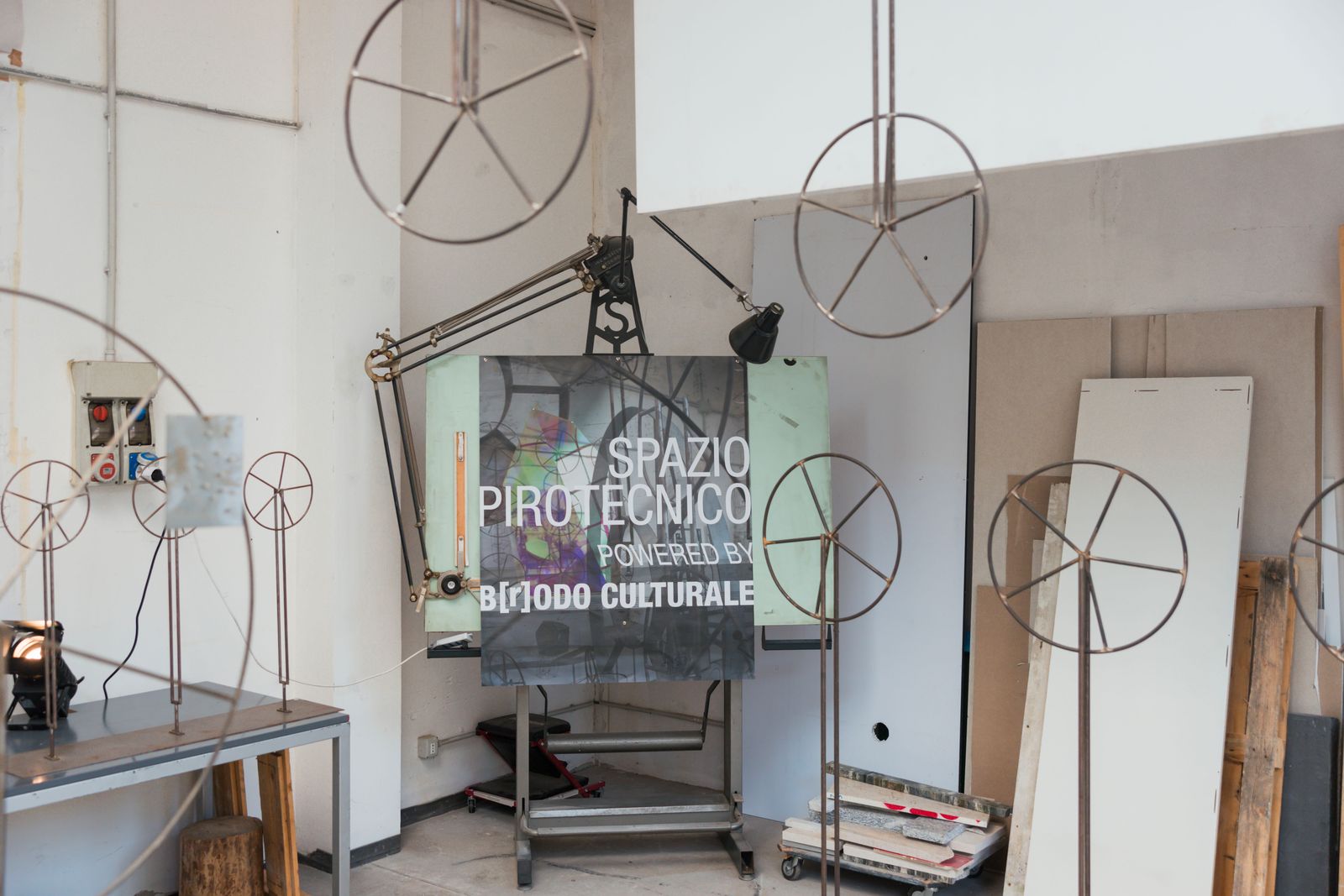 Il pannello Spazio Pirotecnico powered by B[r]odo Culturale tra sculture a forma di ruota