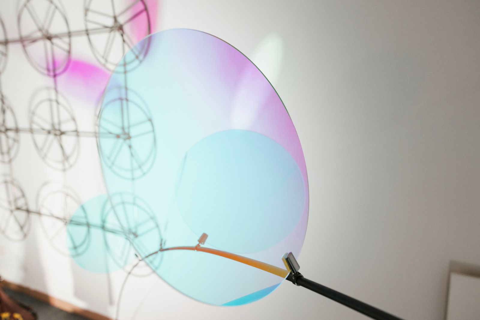 Dettaglio di un disco in plexiglas dicroico dai riflessi cangianti