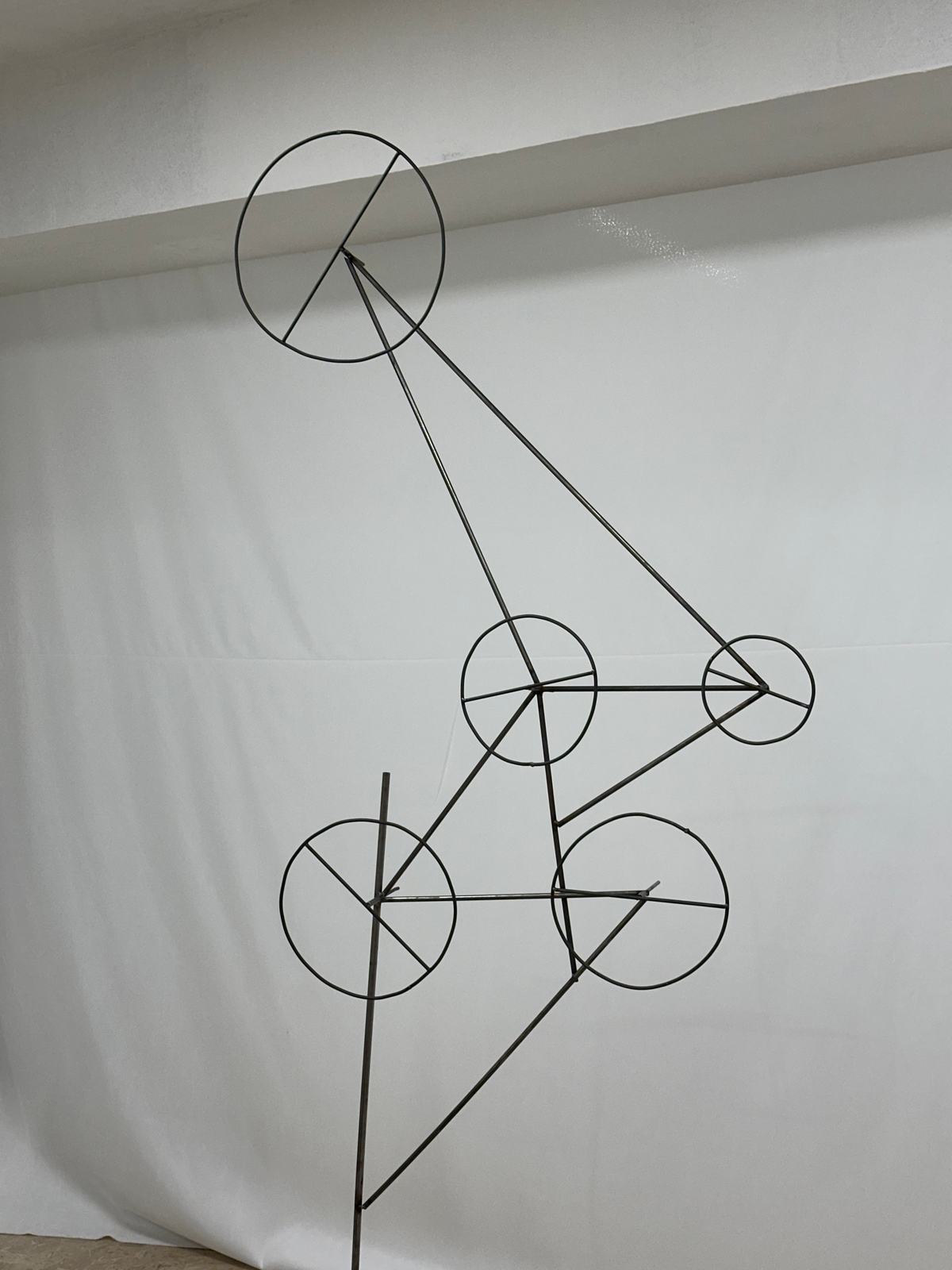 Scultura filiforme in ferro con cerchi su fondo bianco