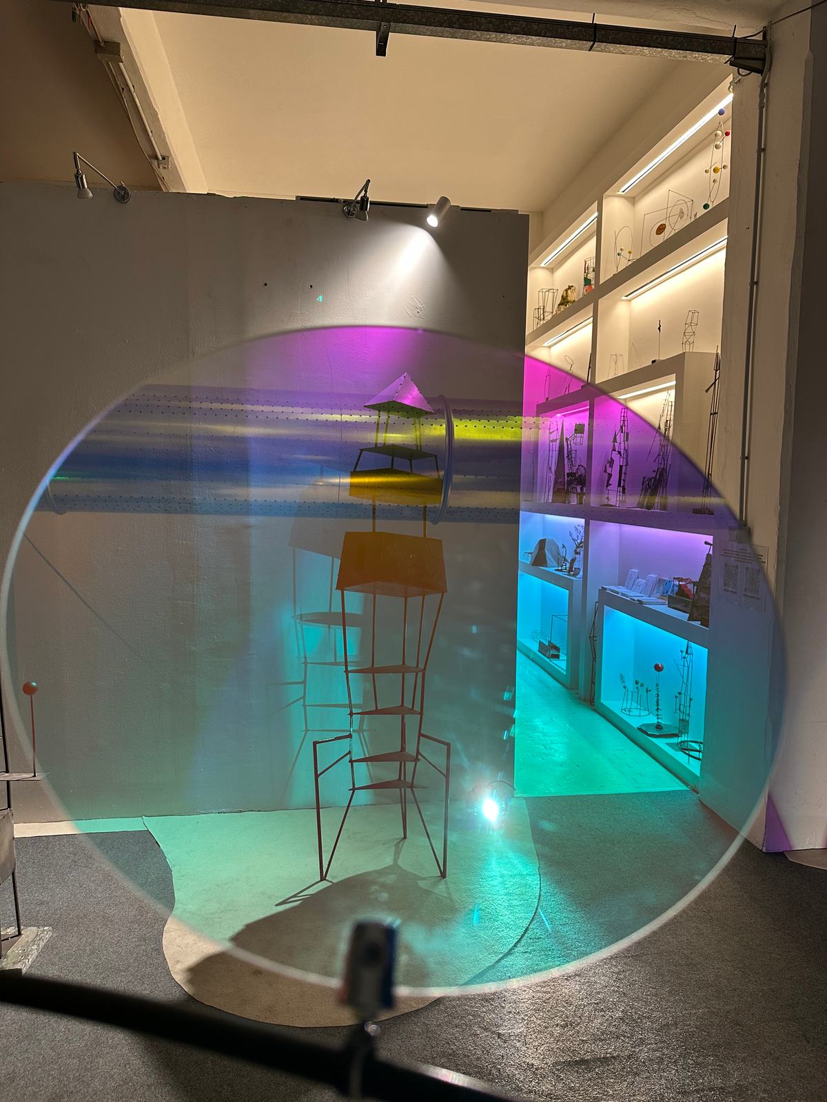 Un grande disco in plexiglas dicroico che riflette lo spazio espositivo