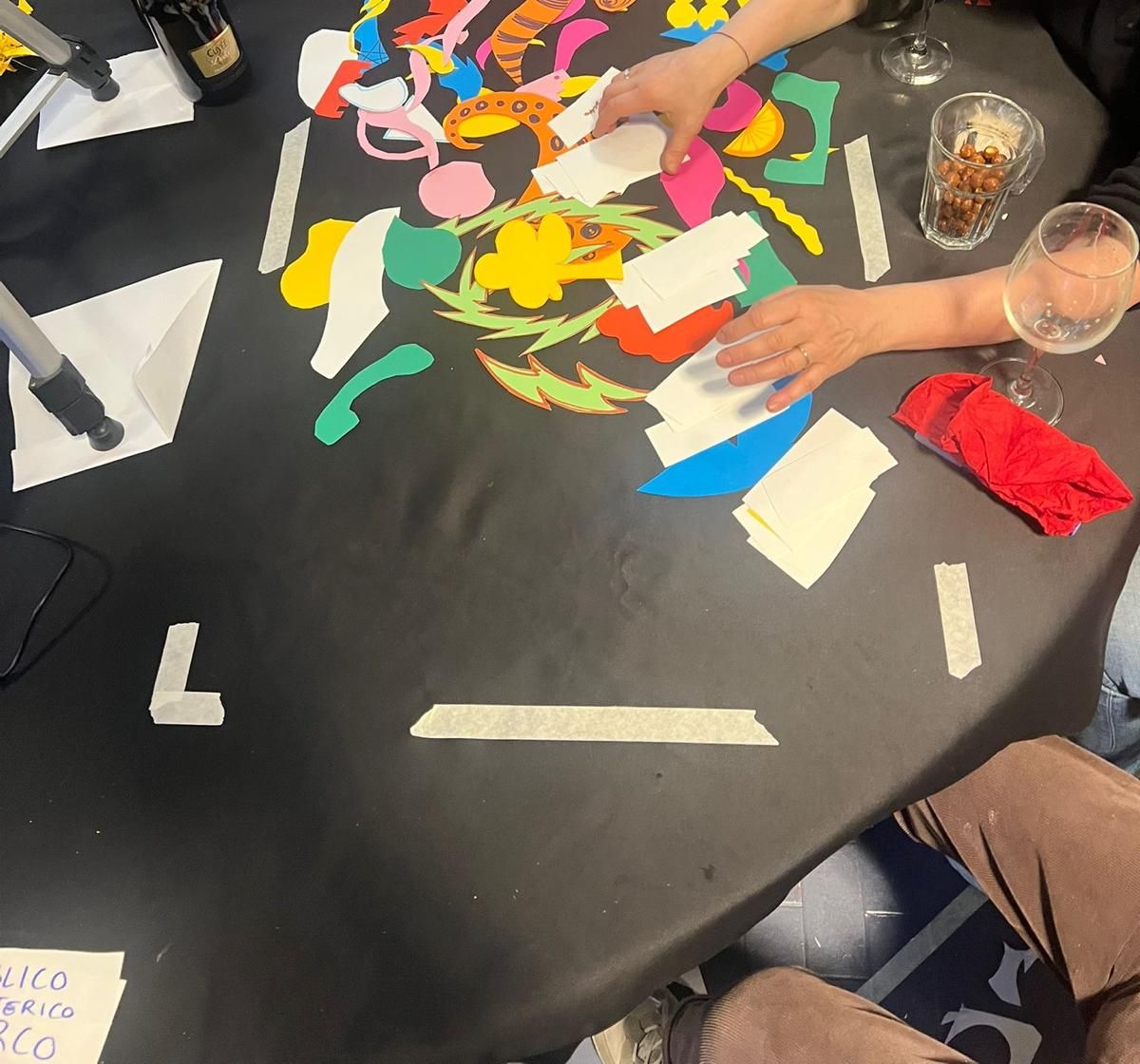 Mani al lavoro su ritagli di carta colorata durante il laboratorio di arte digitale e IA